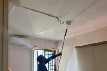 A professional painter from Home Fix SG using a roller to paint the ceiling of a Singapore apartment.