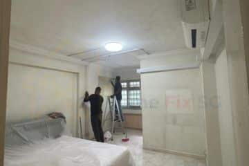 Professional painter from Home Fix SG applying white paint to a ceiling and bedroom walls in a Singapore apartment.