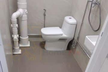 Large white PVC drainage stack pipe and toilet bowl installed in a Singapore bathroom by Home Fix SG.