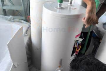 Technicians installing large white storage water heater tanks in a residential property in Singapore.