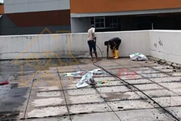 Technicians applying high-quality waterproofing membrane on a large outdoor rooftop to prevent water leakage.